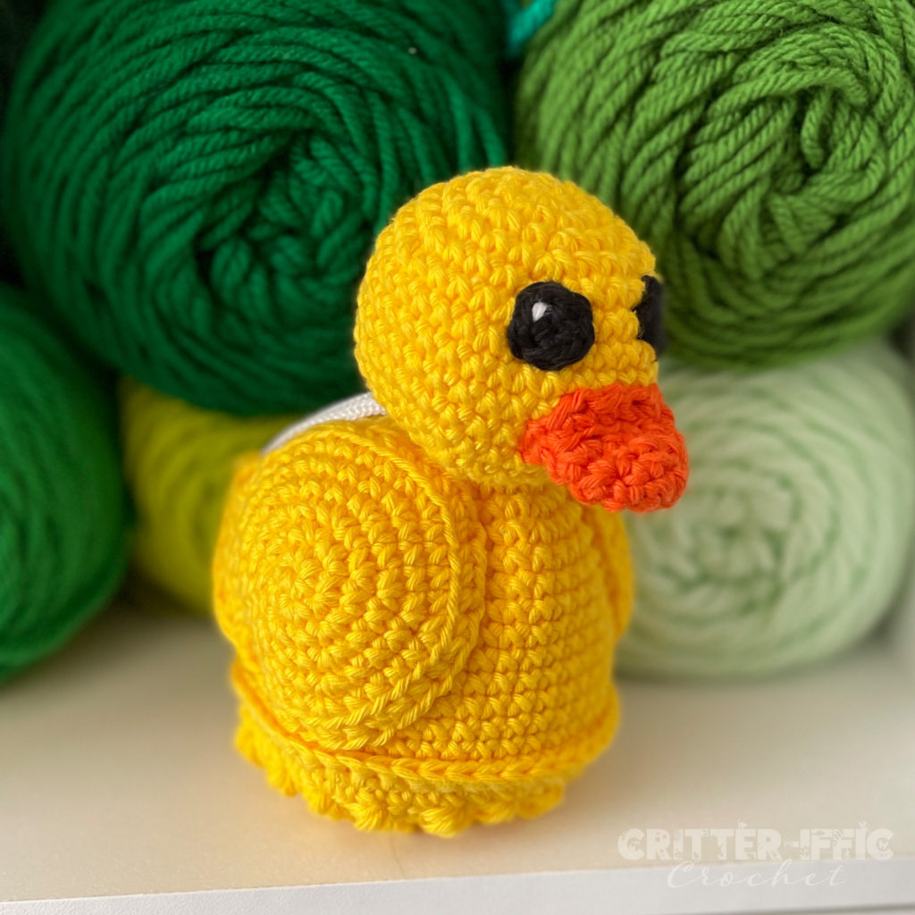 Yellow Darla the Duck Scrubby sitting in front of green yarn
